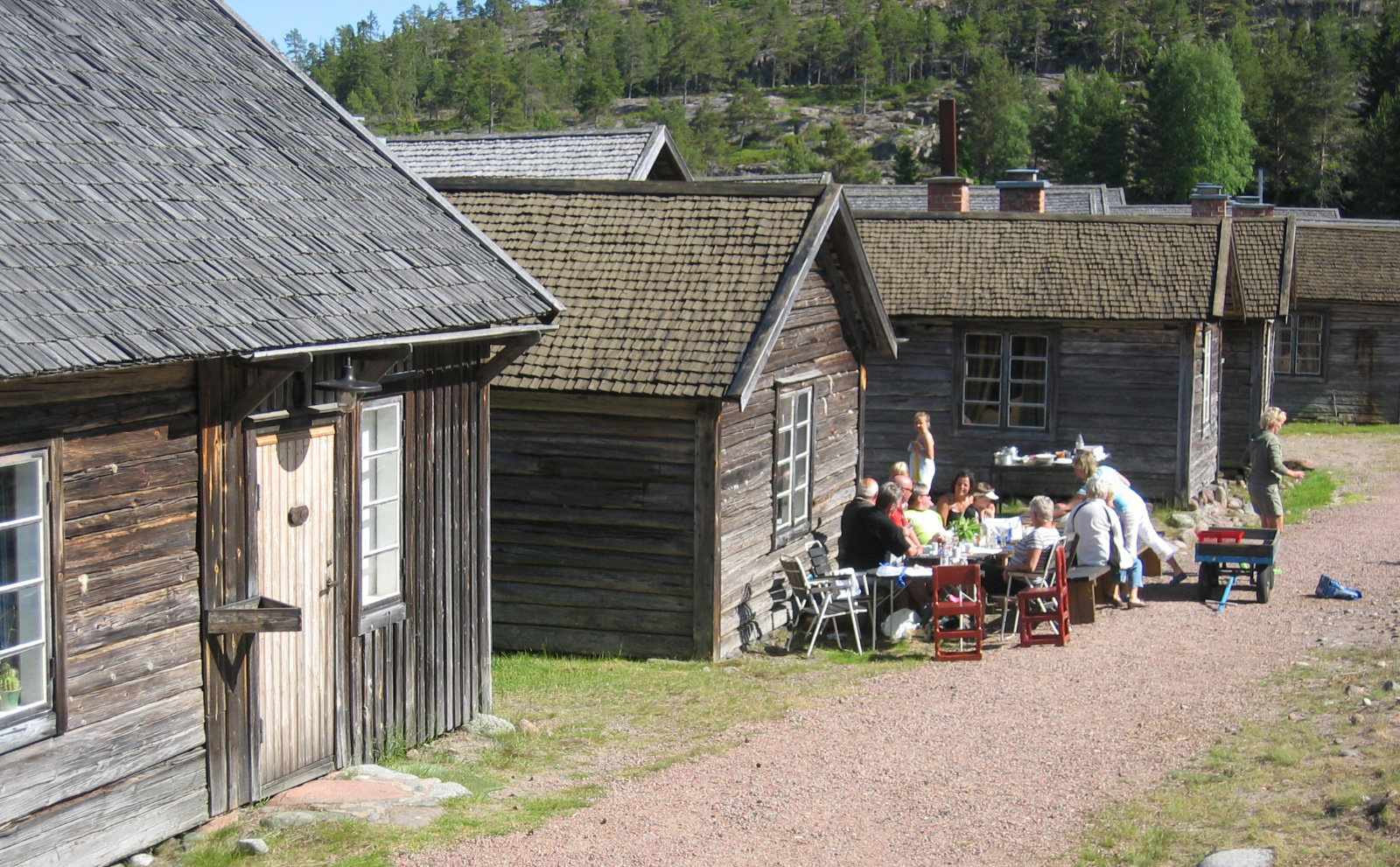 Gamla timrade fiskestugor i Sandviken med gäster som fikar utomhus