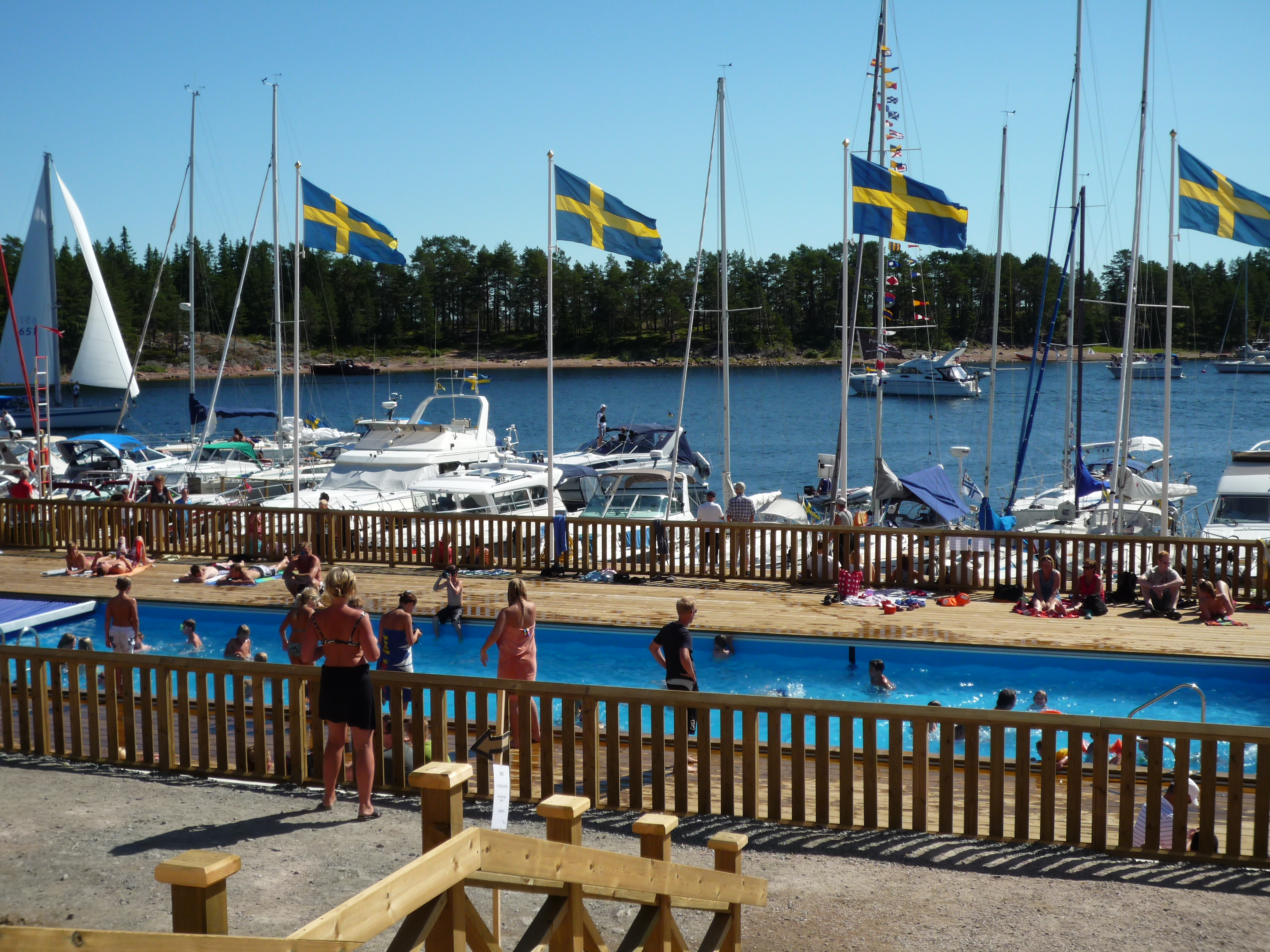 Gästhamnen med båtar och svenska flaggor och poolen vid hotellet