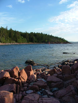 Röda klippor vid Röharn med skogen på andra sidan viken